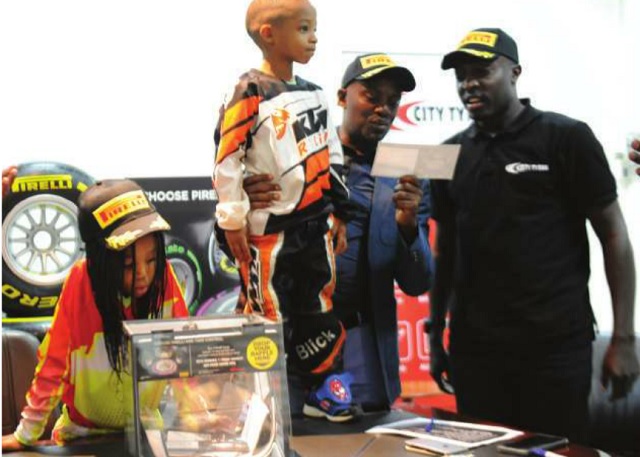 The Independent MD Andrew Mwenda (M) announcing the winner of the trip to the Formula one grand prix in Abu Dhabi. Right is City Tyres Marketing Manager Herbert Bashaasha and left is Isabella Blick, Africa Motor Cross junior champion.