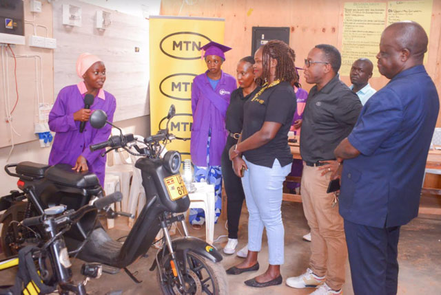One of the girls of the Smart Girls Foundation shows here new skills to Frank Kyazze, the Resident District Commissioner for Kasangati Town Council and the chief guest (right), Josephine Nassiwa, Manager, Wholesale Accounts at MTN Uganda  and MTN Foundations Bryan Mbassa